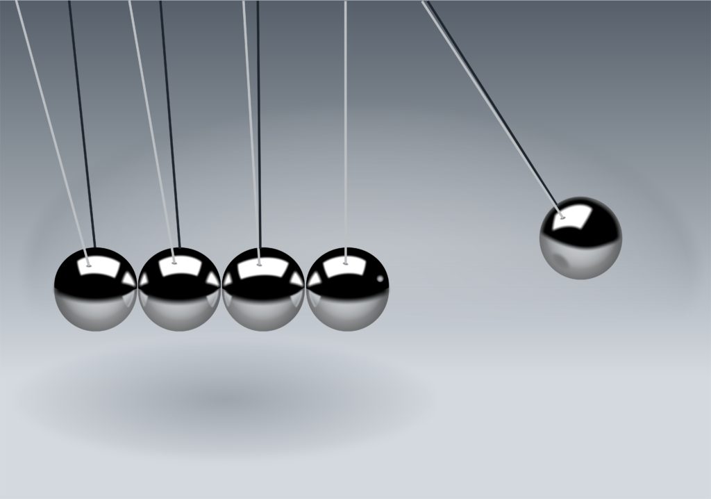 an image of Newton's cradle with one metal ball swinging towards the others