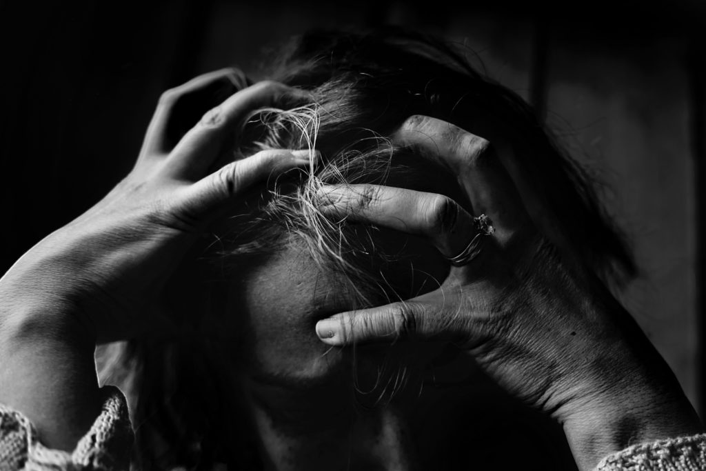 Black and white photo of a woman holding her head in frustration. 