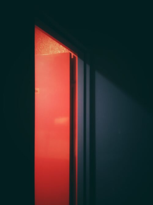 an open door in a dark room that opens to a red room